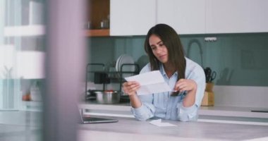 Konsept onaylı proje. Mutfakta duran mavi gömlekli bayan girişimci onaylı mektubu okuyor. Heyecanlı girişimci, onaylanmış proje kadın girişimcisini okuyor..