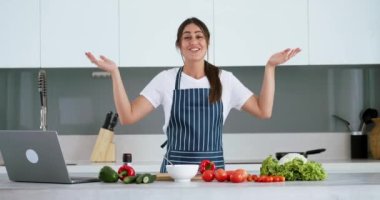 Blog şefi yemek blogu hazırlıyor. Mutfakta önlüklü salata yapan kadın yemek tarifini çevrimiçi yayınında, kadın yemek blogunda ya da yemek pişirme kursunda kameraya anlatıyor.