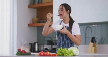 Lezzetli organik salata çiğneyen ve kameraya gülümseyen pozitif genç bir kadın. Organik salata yiyen neşeli kadın portresi. Sağlıklı yaşam tarzı, kilo kontrolü, güzel organik salata..