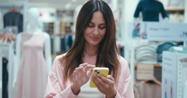 Frau Einkaufszentrum Der Bekleidungsabteilung Lächelt Mit Smartphone Frauen Geben Geld — Stockvideo