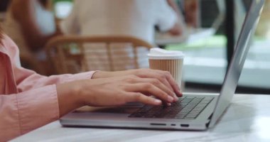 Fotokopi yazarı bilgisayar klavyesine rahat kahve hoparlörüyle metin yazıyor. Kadın ellerinin fotokopi yazarını kapat ve dizüstü bilgisayarın klavyesine kahvehanede metni yaz. Kadın internet üzerinden bir müşteri için metin yazıyor.