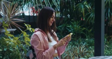 İnternetten alışveriş konsepti. Kafede dinlenen mutlu bir genç, akıllı telefondaki bir sohbette mesaj yazıyor, gülümseyen bir kadın çevrimiçi alışveriş yapıyor, internet tarayıcılarından bilgi arıyor..