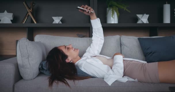 Νεαρή Γυναίκα Ξαπλωμένη Στον Καναπέ Μιλώντας Βίντεο Vlogger Χρησιμοποιώντας Smartphone — Αρχείο Βίντεο