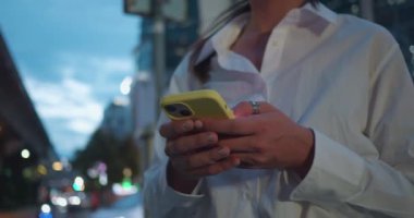 Girişimciye odaklan. Akıllı telefon mesajı yaz. Gece vakti şehrin tam neon ışığı altında dur. Akıllı telefon girişimcisiyle mesajlaşan kadın akıllı telefon mesajlaşması sosyal medya paylaşımı, haber ekranı kaydırma.