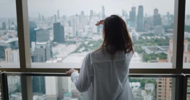 Resmi takım elbiseli bir kadın kariyerinde ilerisini düşünüyor. Kariyer büyüme arzusu kavramı. Beyaz gömlekli kadın, şehir kariyerinin gelişiminin arka planında iş kurma terasında duruyor.