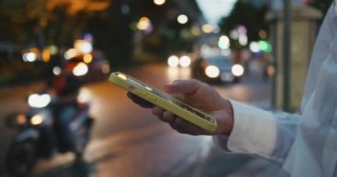 Gece şehir caddesinde neon ışıklarla dolu duran akıllı telefonu kullanarak kadın eline odaklan. Akıllı telefon kullanan bir kadın. Akıllı telefon, sosyal medya ve online alışveriş kullanan bir kadın..