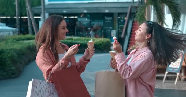 女性は 明るい感情を示すアイスクリームを食べるストリートに立ち アイスクリームは笑顔をもたらします 幸せな喜びの友情でアイスクリームの喜び 甘い味を救う 一緒に楽しい瞬間 — ストック動画