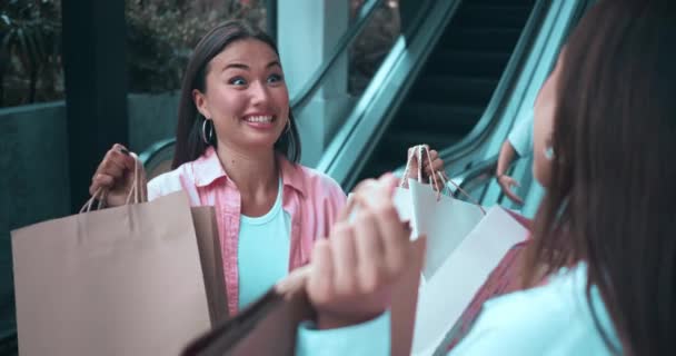 2人の友人のショッピングモールは 女性の感情を放射するショッピングでいっぱいのバッグを展示しています 女性の感情は喜びを明らかに笑顔を笑います 感情は幸福を反映しています エレガンス ショッピング スリー — ストック動画