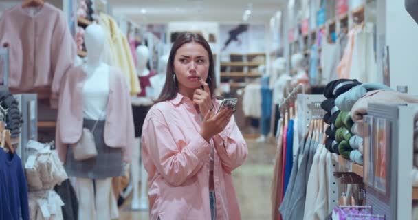 服装店里的女人发短信电话散发出喜悦 结合购物技术快乐的现代生活找到了完美的装束 购物带来的快乐象征着繁荣技术精湛的优雅 — 图库视频影像