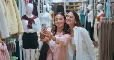 Arkadaş giyim mağazasında selfie çekerken kadınların yakın çekimlerinde gülüşmeleri mutluluk alışveriş anları yakalıyor. Kadınların mutluluğu modadır. Mutlu deneyimler yaşar. Kadınların mutluluğu her gülüşünde.