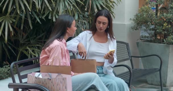 Két Női Barát Egy Padon Beszélgetnek Telefonnal Megtestesítik Női Barátságot — Stock videók