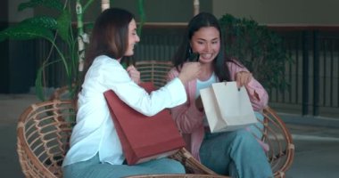 Yedek kulübesinde alışveriş yapan iki arkadaş alışveriş zevkini paylaşıyor. Alışverişin neşesi kahkahalarda yansıyor alışveriş kadınlarının arkadaşlığının neşesi paylaşılan kutlamaların tadı yeni keşiflerin neşesi