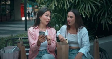 Kadın arkadaşlar bankta oturup, pozitif iletişimi somutlaştıran telefonlar kullanıyorlar. Pozitif iletişim, paylaşılan sevinç, pozitif iletişim, içtenliğin zarafetini harmanlıyor.