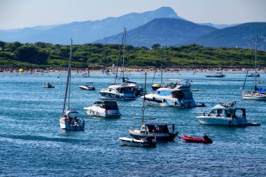 Muhteşem bir yelkenli ve eğlence teknesi Plage La Bandine sahilinin önünde, deniz ve dağ manzaralarıyla çevrili..