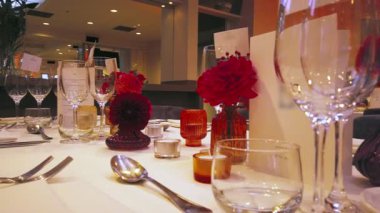 Zarif sofra takımları, renkli cam süsleme parçaları ve canlı çiçek düzenlemelerinin yer aldığı güzel düzenlenmiş bir yemek masasının alçak açılı penceresi festival toplantıları veya düğün resepsiyonları için uygundur..