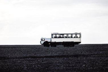 Güney İzlanda 'da Selheimasandur' un siyah kumsalında turistleri gezdiren bir araba. Yüksek kalite fotoğraf