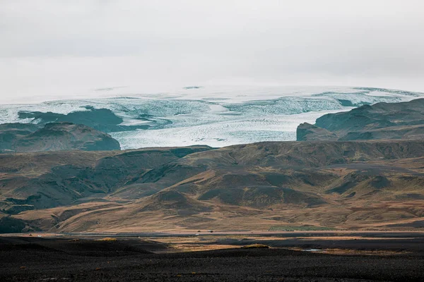 冰岛的黑色火山灰沙滩 朝向大陆 有一条河流流过 水面上有一些黄色的叶子 — 图库照片