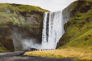 Skoga nehrinde ünlü Skogafoss şelalesi. Şelalenin altında duran turist kalabalığı. İzlanda, Avrupa. Manzara fotoğrafçılığı. Yüksek kalite fotoğraf