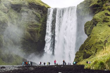 Skoga nehrinde ünlü Skogafoss şelalesi. Şelalenin altında duran turist kalabalığı. İzlanda, Avrupa. Manzara fotoğrafçılığı. Yüksek kalite fotoğraf