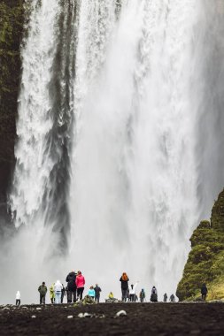 Skoga nehrinde ünlü Skogafoss şelalesi. Şelalenin altında duran turist kalabalığı. İzlanda, Avrupa. Manzara fotoğrafçılığı. Yüksek kalite fotoğraf