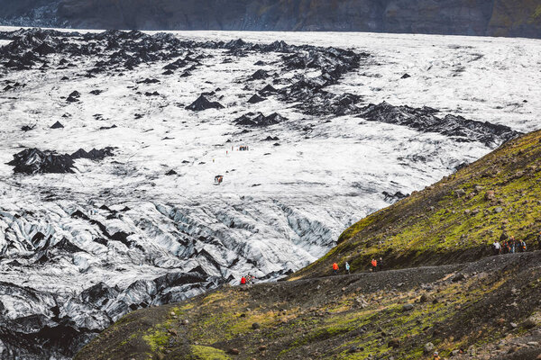 Hikers unrecognizable on the Solheimajokull Glacier, Iceland, Panoramic view. High quality photo