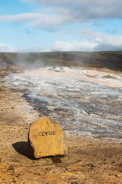アイスランドの間欠泉と温泉から噴出する蒸気の垂直写真 前方にサイン間欠泉のある石 — ストック写真