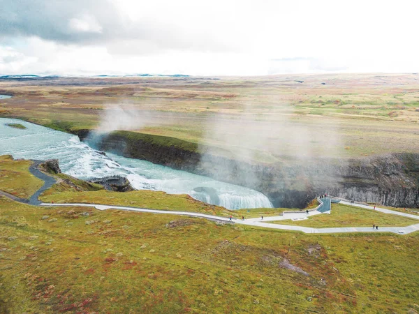 아이슬란드 거대하고 아름다운 아래로 떨어지면서 거품이 흐르는 관광객들은 번둘러보면서 폭포를 — 스톡 사진