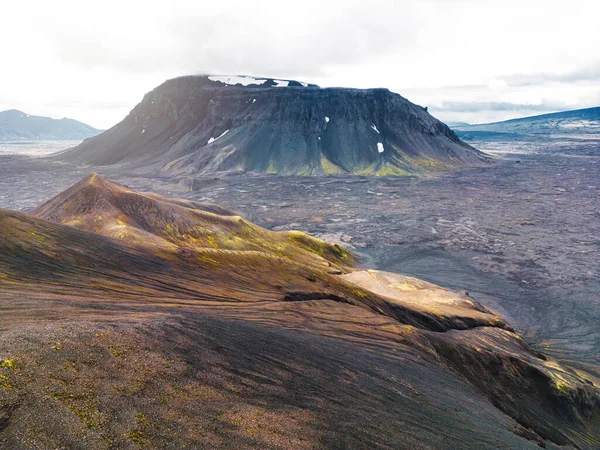 遥远的火山降落在冰岛大陆的某个地方 周围环绕着生机勃勃的绿色灌木丛和火山土地 火山岩形成 黑色灰色火山岩 没有人 — 图库照片