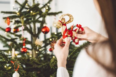 Noel ağacını süsleyen, ağaca kırmızı bir süs takan, elinde kırmızı bir Noel süsü tutan tanınmamış beyaz kadın.. 