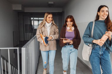 Üç arkadaştan oluşan bir grup, genç beyaz kız öğrenci bir mola sırasında okulun içinde yürürken, başka bir sınıfa yöneldiler. Öğrenciler kitaplarını yanlarında taşıyor.. 