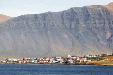 Batı İzlanda 'daki Stykkisholmskirkja Limanı' nın güzel hava manzarası ve balıkçı gemileri İzlanda 'nın Stykkisholmur kasabasında. Sugandisey Kayalıkları 'ndan deniz feneriyle şehir manzarası. Ünlü renkli evler.