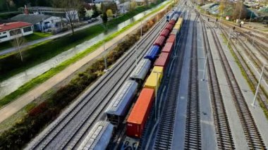 Kargo trenleri yakın plan. Tren istasyonundaki renkli yük trenlerinin hava manzarası. Demiryolunda malları olan vagonlar. Ağır endüstri. Trenli endüstriyel kavramsal sahne. Uçan İHA 'nın üst görüntüsü