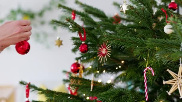 用红色饰物装饰圣诞树的高加索女人的慢镜头 天然圣诞树 红白相间的装饰品 节假日 圣诞彩灯 — 图库视频影像
