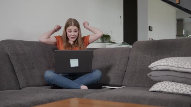 Aufgeregte Junge Kaukasische Frau Sitzt Auf Der Couch Mit Laptop — Stockvideo