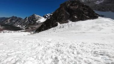 Güneşli bir günde POV kayak turu, kış yavaş yavaş sona eriyor ve bahar başlamak üzere, dağlarda hala çok kar var. Güneşli bir günde gökyüzünde kayak turisti.