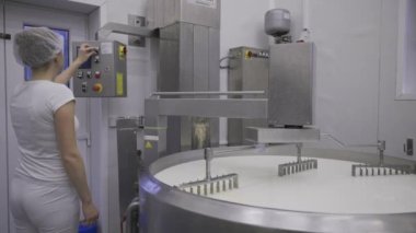Caucasian women working at the dairy farm on the production line, packaging product, operating with machines mixing the milk, and making cheese curds. Dairy factory worker wearing all white uniform