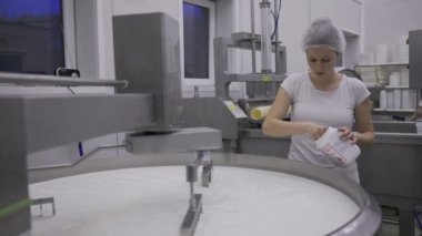 Caucasian women working at the dairy farm on the production line, packaging product, operating with machines mixing the milk, and making cheese curds. Dairy factory worker wearing all white uniform