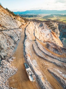 Aerial view of open pit quarry with heavy machinery working on the grounds. Excavators and trucks driving on the grounds. Sunny day in the countryside. 