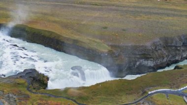 Huge beautiful waterfall Gullfoss, famous landmark in Iceland. River foaming whilst falling down the waterfall, tourist waling by, looking at the waterfall from a view point. High quality video