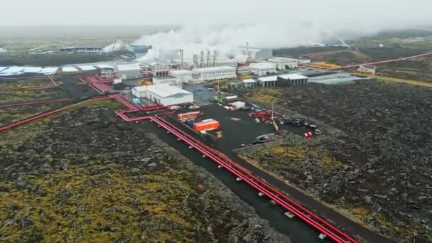 地热发电厂 冰岛的热水发电厂 蒸汽从工厂的烟囱里滚出来 红色的大管子穿过充满热水的地面 可持续 — 图库视频影像
