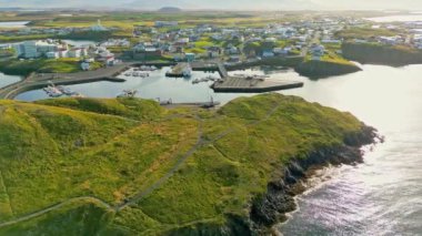 Batı İzlanda 'daki Stykkisholmskirkja Limanı' nın güzel hava manzarası ve balıkçı gemileri İzlanda 'nın Stykkisholmur kasabasında. Sugandisey Kayalıkları 'ndan deniz feneriyle şehir manzarası. Ünlü renkli evler.