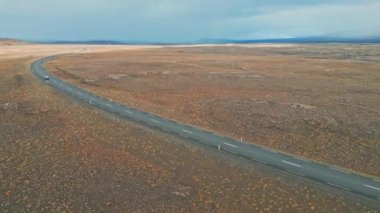 İzlanda dağları, F yolları, nehir geçidi. İzlanda 'da bir yerlerde uzak toprak yol, canlı yeşil çalılar ve volkanik arazilerle çevrili. Çakıl yolunda tek başına giden bir araba.. 