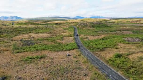 アイスランドの高地 F道路 川を渡る 緑の茂みと火山の土地に囲まれたアイスランド本土のどこかに離れた未舗装の道路 砂利道を一人で運転する車 — ストック動画