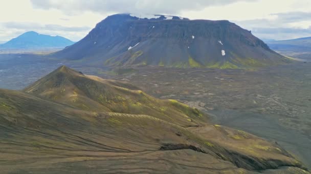 緑豊かな茂みと火山の土地に囲まれ アイスランド本土のどこかにリモート火山の土地 火山岩の形成 小さな山 黒灰色の火山岩 人はいない — ストック動画