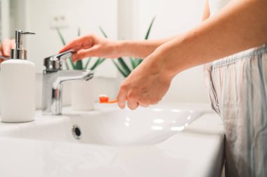 Young caucasian woman getting ready in a bright white modern bathroom. Woman doing her skincare, cleaning her face, teeth and body int he bathroom. 