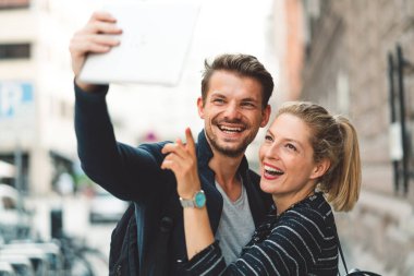 Young millennial couple living in the city, taking a selfie with a smart phone. 