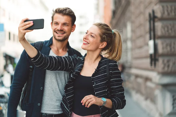 Young millennial couple living in the city, taking a selfie with a smart phone. 