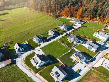 Aerial view, drone flying over new housing development in the country side. Family homes in the suburbs surrounded with forest and green fields. 