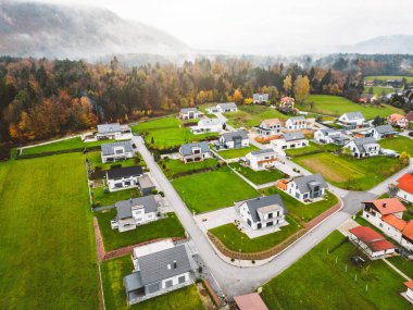 Aerial view, drone flying over new housing development in the country side. Family homes in the suburbs surrounded with forest and green fields. 