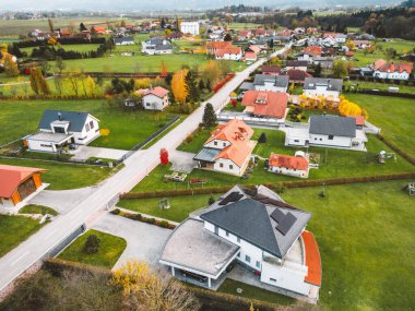 Aerial view, drone flying over new housing development in the country side. Family homes in the suburbs surrounded with forest and green fields. 